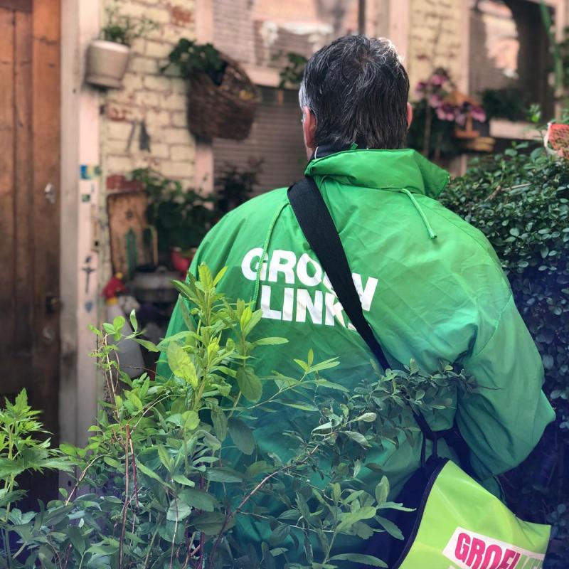 Een GroenLinks-vrijwilliger met een groene campagnejas aan en een GroenLinks-tas om